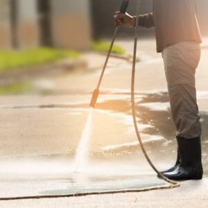 Person using a pressure washer to clean a driveway